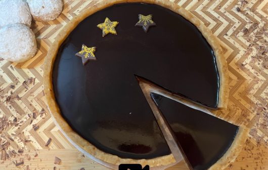 Συνταγή για μοναδική τάρτα σοκολάτας. Αν σας περίσσεψαν κουραμπιέδες δοκιμάστε αυτήν την υπέροχη τάρτα με βάση από κουραμπιέδες, γκανάς σοκολάτας και υπέροχο γυαλιστερό γλάσο.