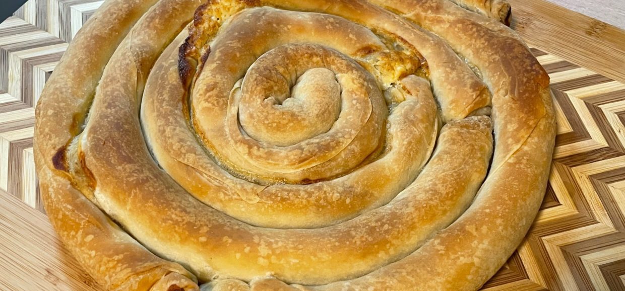 Συνταγή για στριφτή τυρόπιτα με χειροποίητο τραγανό φύλλο και υπέροχη γέμιση με φέτα, κίτρινο τυρί και γιαούρτι.