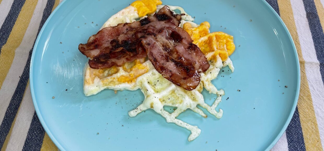 Αυγά με μπέικον στη βαφλιέρα. Ο συνδυασμός τα λέει όλα από μόνος του. Σερβίρουμε με ελαιόλαδο και πιπέρι.