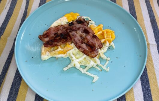 Αυγά με μπέικον στη βαφλιέρα. Ο συνδυασμός τα λέει όλα από μόνος του. Σερβίρουμε με ελαιόλαδο και πιπέρι.