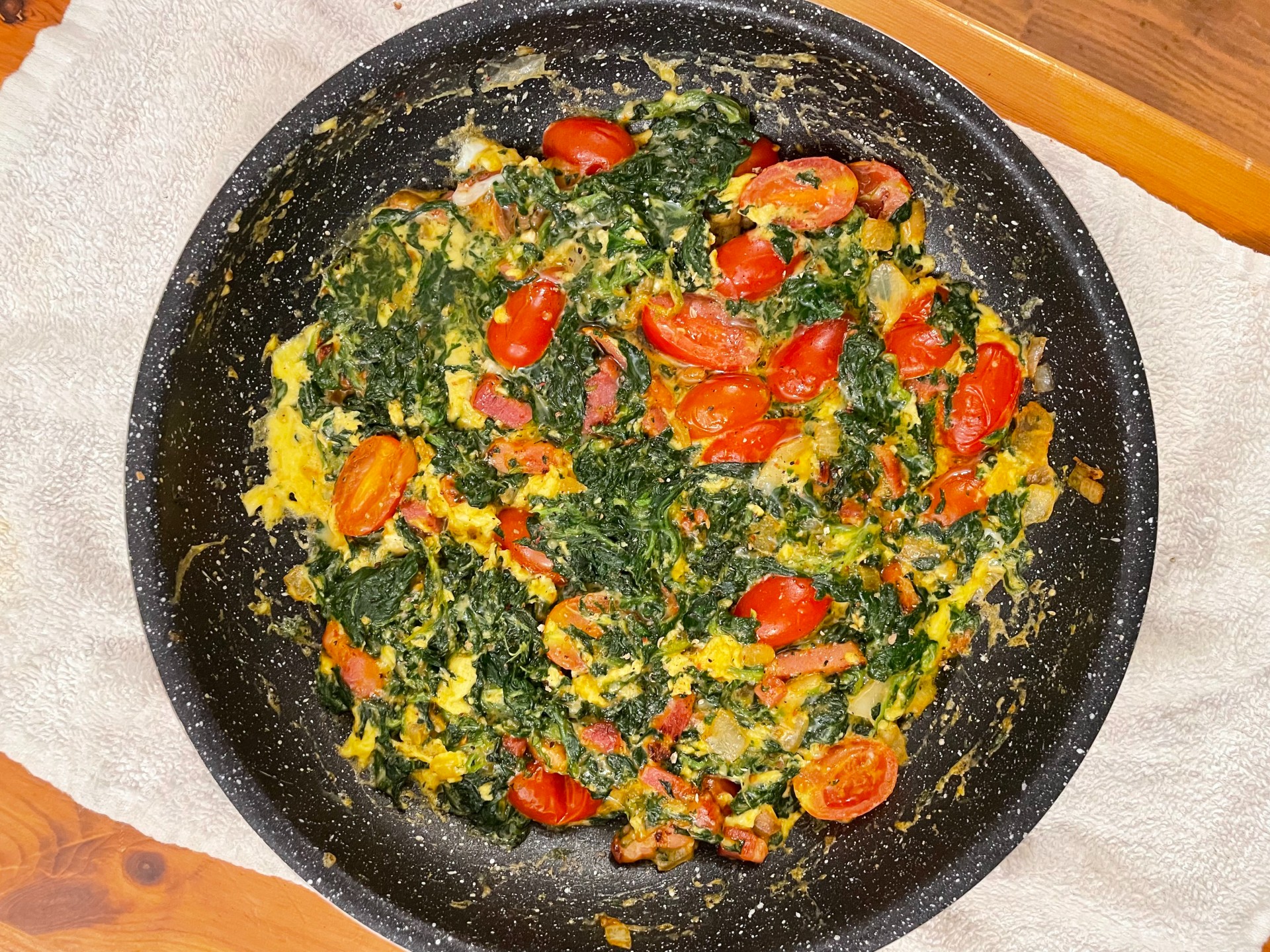 Εύκολη και γρήγορη ομελέτα με σπανάκι, μπέικον, κρεμμύδι, τοματίνια και παρμεζάνα. Ιδανική για θρεπτικό πρωινό ή ελαφρύ γεύμα.