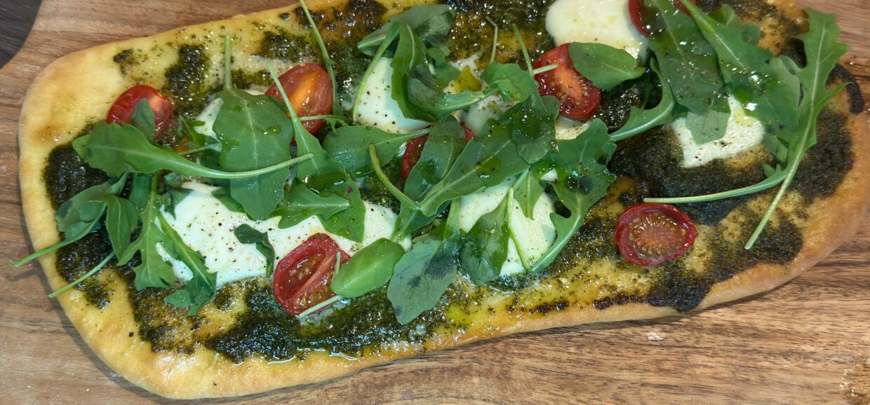 Φτιάξε πανεύκολο flatbread με πέστο, μοτσαρέλα, ντομάτα και ρόκα σε λίγα λεπτά. Τραγανή βάση, πλούσια γεύση.