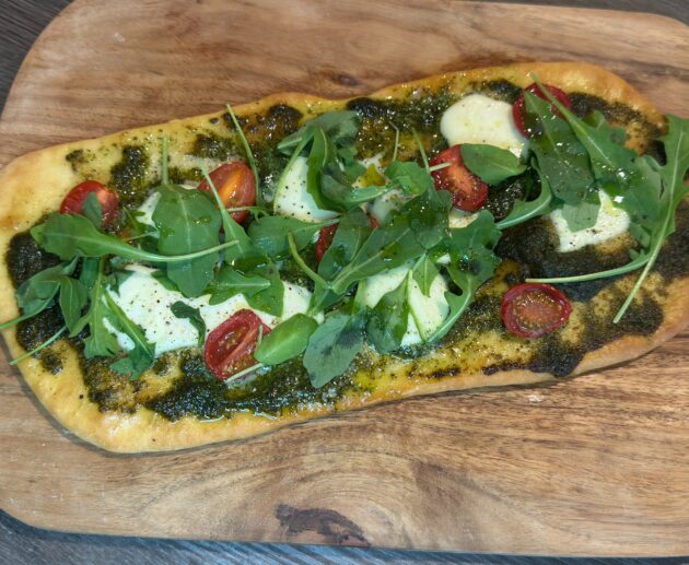 Φτιάξε πανεύκολο flatbread με πέστο, μοτσαρέλα, ντομάτα και ρόκα σε λίγα λεπτά. Τραγανή βάση, πλούσια γεύση.